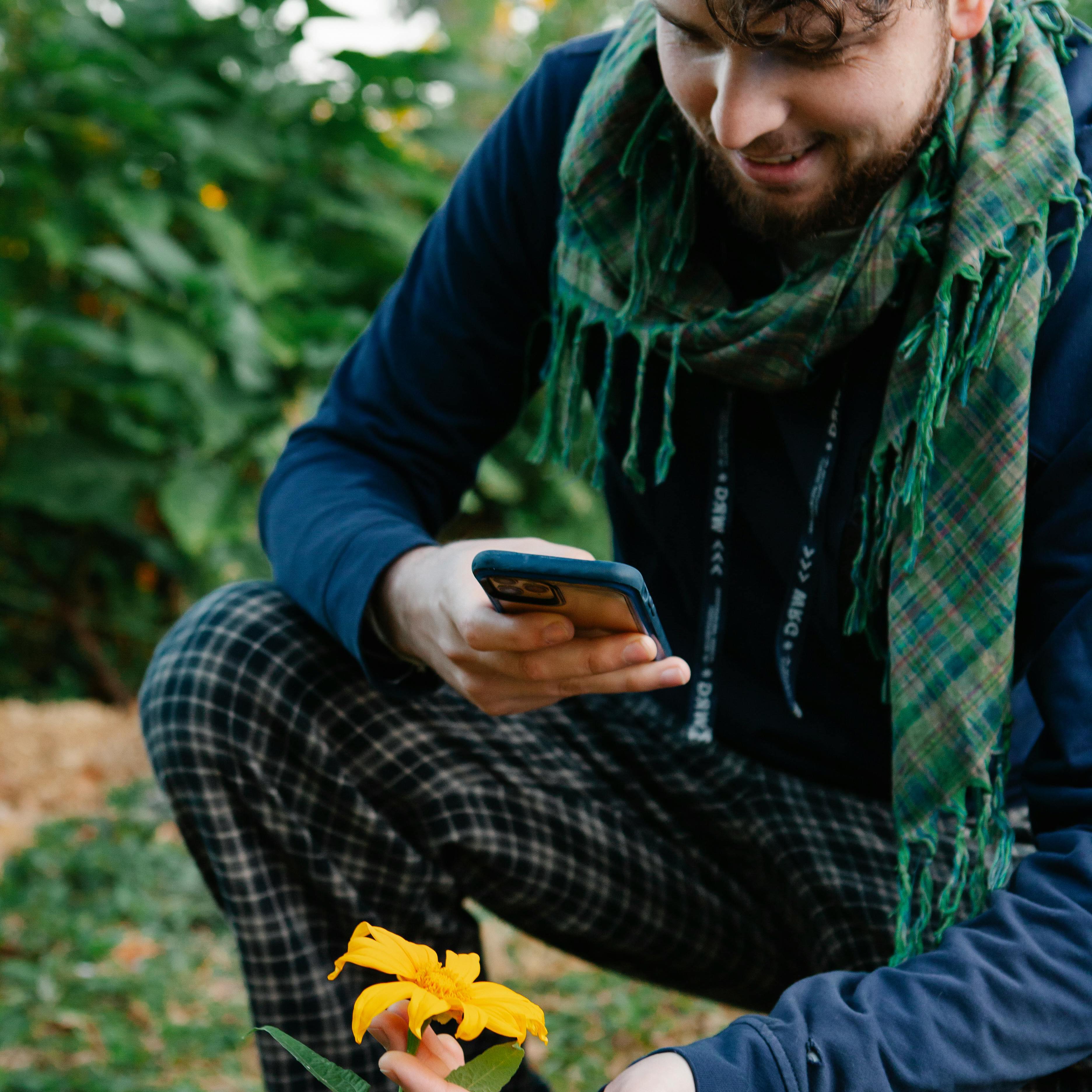 スマホで花を撮る男性の画像